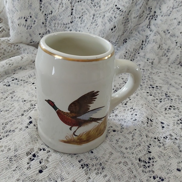 A Hall Heirloom China ivory ceramic mug from the Waterfowl Series by L. Banks is a pheasant trimmed in gold, made in USA.  Bar  1095