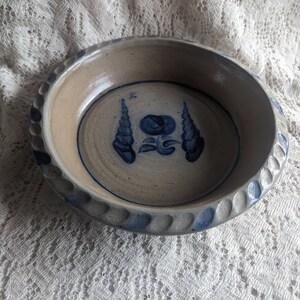 May include: A blue and white stoneware bowl with a floral design. The bowl has a scalloped edge and a textured rim.