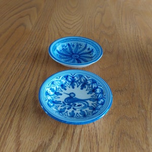 May include: Two blue and white ceramic bowls with intricate floral designs. The larger bowl features a bird design in the center.