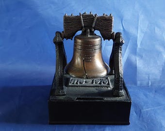 A 1976 black cast iron Bicentennial bronze colored coin bank 1776-1976 in the form of a swinging Liberty Bell with a clapper.   Misc 2073