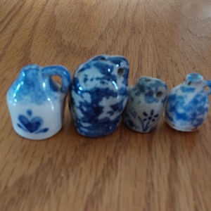 May include: Four miniature blue and white ceramic jugs with a traditional design. The jugs are all different shapes and sizes.