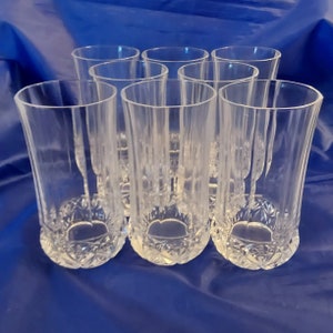 May include: Set of eight clear glass tumblers with a diamond-shaped pattern. The glasses are arranged in a circle.
