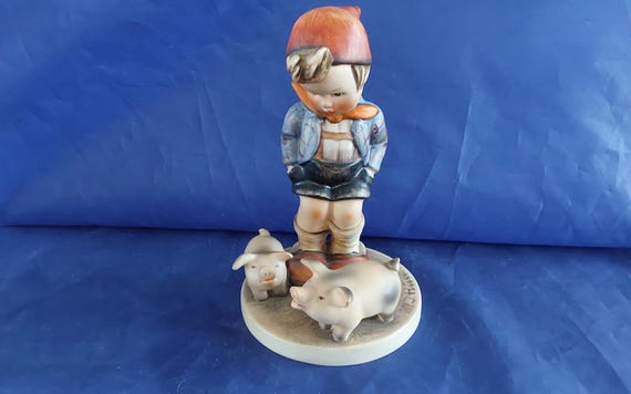 A vintage Farm Boy with Piglets-number 66, marked M J Hum on the top and "V" with a bee-W Germany blue backstamp 1960s.  Misc 2051