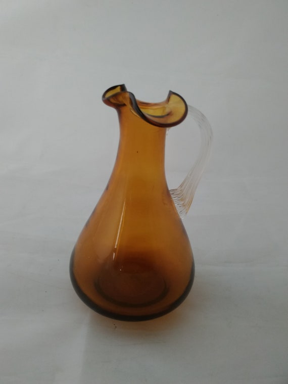 A Small Clear Hand Blown Glass Amber Glass Pitcher With a Pinched