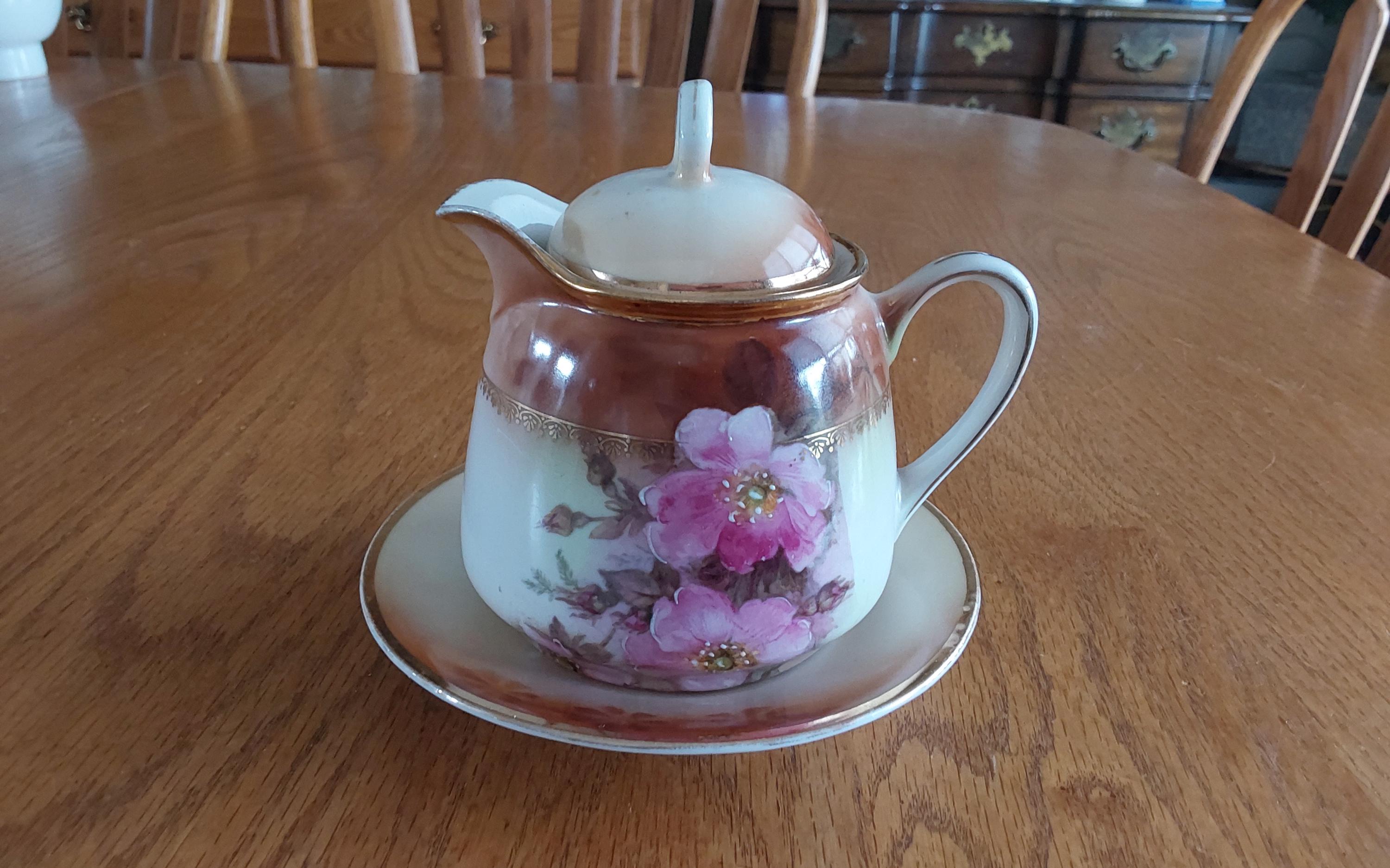 An antique white porcelain syrup pitcher with matching lid and underplate from Germany, in brown tones with pink flowers.  Dish 1997