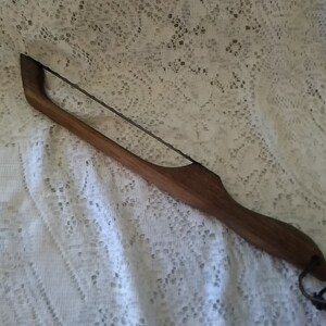 May include: A wooden bread knife with a metal blade and a leather loop at the end of the handle.