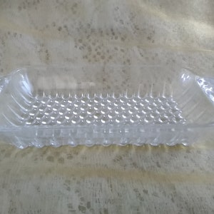 By Anchor Hocking, a clear glass relish dish in the Dew Drop pattern of dotted glass with scroll handles.  Bowl 1140