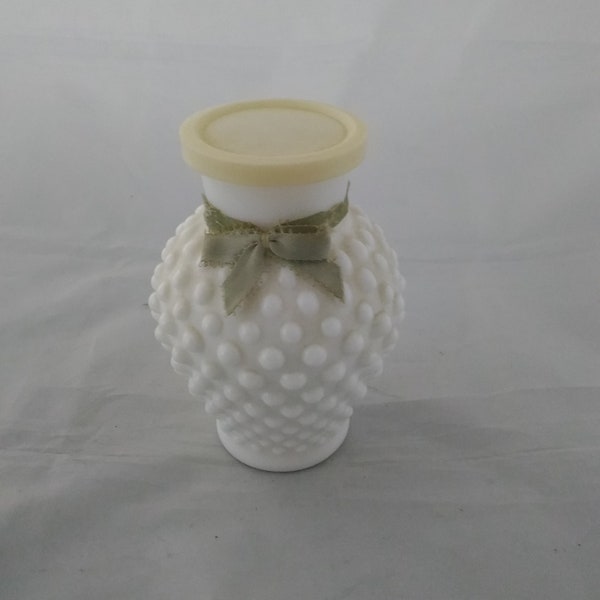 An Avon white milk glass hobnail vase filled with bubble bath still inside.  Avon C 62