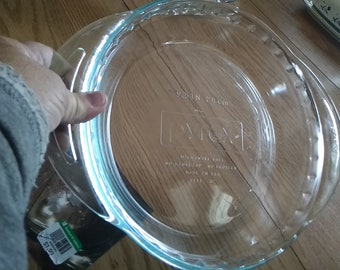 A barely used Pyrex clear 9.5" glass pie plate with a fluted rim and handles.  Dish 1135