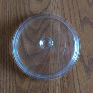 May include: A white ceramic mug with a black handle and the text "But First, Coffee" in a handwritten style. The mug is on a white surface. The mug is 4 inches tall.