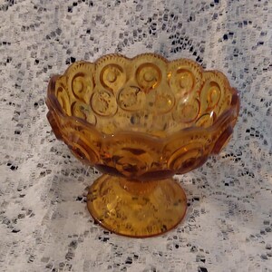 A LE Smith amber gold stemmed glass compote in their famous moon and stars pattern that stands 5 inches tall.  Bowl 1619