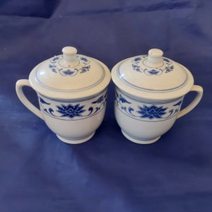 A pair of white Asian handled 11 oz pedestal tea cup with a vented lid to allow for steeping with a blue floral design.  Glass 656