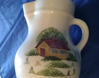 A ivory ceramic N.S. Gustin Co water pitcher with a hand decorated log cabin in the woods.  Pitcher 44