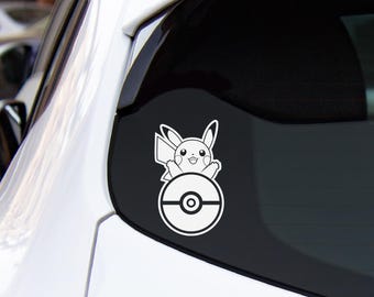 Può includere: Un adesivo in vinile bianco applicato sul lunotto posteriore di un'auto bianca. L'adesivo presenta un'illustrazione a linee del personaggio Pikachu che emerge dalla parte superiore di una Poké Ball circolare, con un contorno bianco.