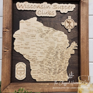 May include: A wooden map of Wisconsin with the text "Wisconsin Supper Clubs" at the top. The map is decorated with a compass and a fork and knife. The map is filled with the names of supper clubs throughout the state.