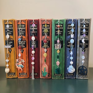 May include: A set of ten colorful beaded bookmarks with charms, each attached to a vintage book with the title "Junior Classics". The charms include a butterfly, a flower, a star, a cactus, a dragonfly, a heart, a crescent moon, a pentagram, a tassel, and a cherub.