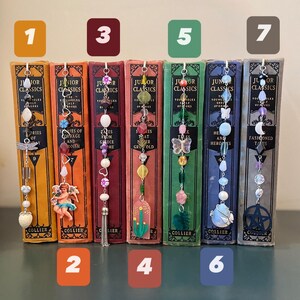 May include: Seven bookends with different colored beads and charms. The bookends are made of metal and have a vintage look. The charms include a dragonfly, an angel, a tassel, a cactus, a butterfly, a seashell, and a pentagram.