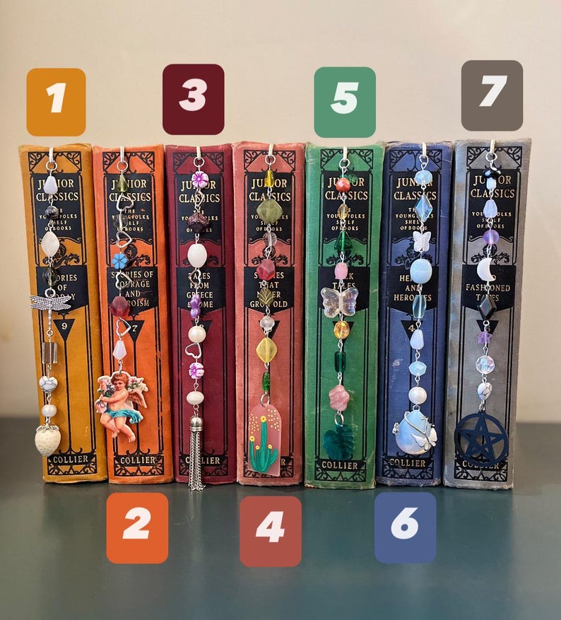 May include: Seven bookends with different colored beads and charms. The bookends are made of metal and have a vintage look. The charms include a dragonfly, an angel, a tassel, a cactus, a butterfly, a seashell, and a pentagram.