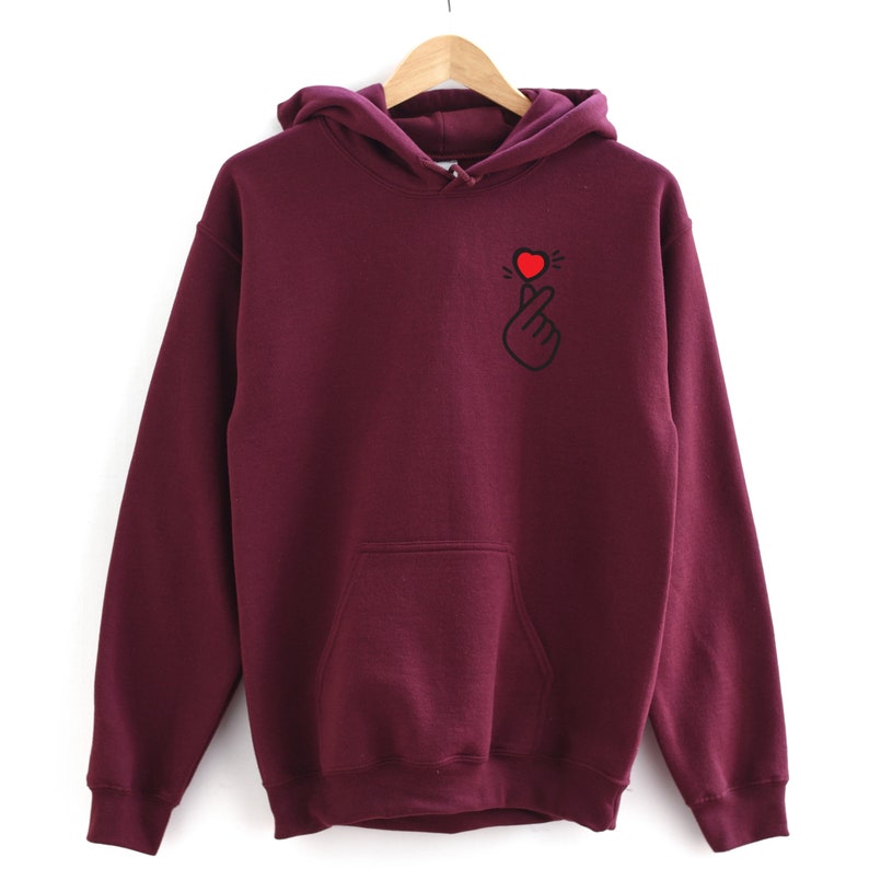 May include: Burgundy hooded sweatshirt with a black and red heart hand gesture graphic on the front.