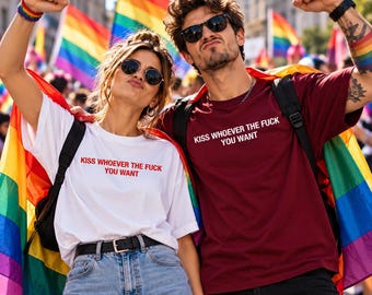 May include: A white t-shirt and a maroon t-shirt, both featuring the text KISS WHOEVER THE FUCK YOU WANT in a simple font. The white shirt is paired with light blue denim jeans and a black belt, while the maroon shirt is worn with black pants.