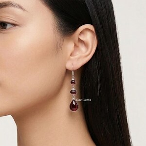 Könnte beinhalten: Eine weiße Keramik-Tasse mit schwarzem Henkel und dem Text "But First, Coffee" in fetter, schwarzer Schrift. Die Tasse steht vor einem verschwommenen Hintergrund, der eine gemütliche Umgebung andeutet.