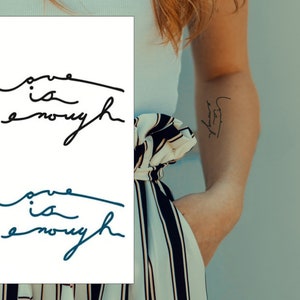 Peut inclure: Deux tatouages temporaires avec la phrase "L'amour suffit" écrite en cursive. Le tatouage du haut est noir et le tatouage du bas est bleu.
