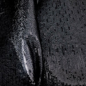 May include: Black sequined fabric with a shiny, iridescent finish. The fabric is folded in half, showing the texture of the sequins.