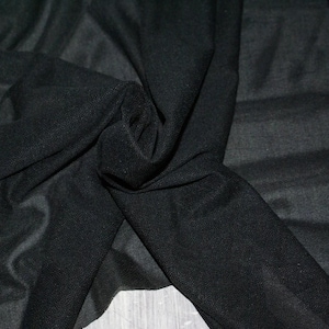 May include: Black sheer fabric with a soft, smooth texture. The fabric is draped and folded, showing its delicate and flowing nature.