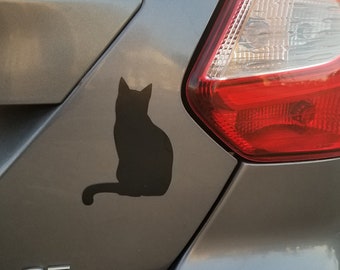 May include: A black cat silhouette sticker is affixed to the gray rear of a car. The sticker is positioned near the right taillight. The car's SE Flex Fuel emblem is visible.