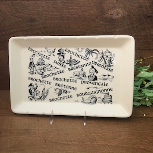 Puede incluir: Bandeja de servir de cerámica blanca con ilustraciones en blanco y negro de diferentes tipos de alimentos y el texto "Brochette" y los nombres de diferentes regiones de Francia.