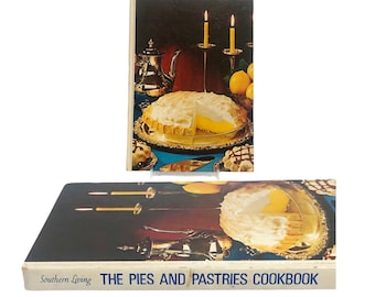 Puede incluir: Un libro de cocina vintage titulado "The Pies and Pastries Cookbook" de Southern Living. La portada presenta un pastel de merengue de limón con una rebanada cortada, rodeado de velas y limones.