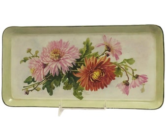 May include: A vintage metal tray with a green rim and a white background. The tray features a floral design with pink, red, and white flowers.