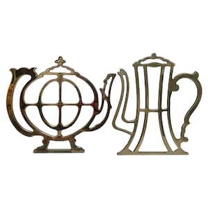 Puede incluir: Dos posavasos de metal dorado en forma de tetera y cafetera. Los posavasos son calados y tienen un diseño decorativo.