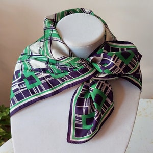 May include: A white, green, and purple patterned silk scarf with a geometric design. The scarf is tied around a white mannequin's neck.