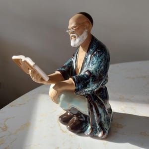 Statuetta in ceramica smaltata raffigurante un uomo di fango cinese accovacciato che legge, risalente alla metà del secolo scorso