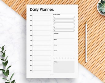 May include: A black and white daily planner with a simple design. The planner has sections for to-do list, meals, and notes.