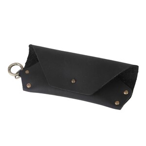 May include: Black leather glasses case with a metal clasp and rivets.