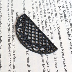 May include: Black metal half-circle decorative piece with a geometric and floral design. The piece is made of a delicate, intricate pattern.