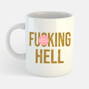 May include: White ceramic coffee mug with a gold glitter design that says "F***ING HELL" with a pink circle censoring the first word. The circle has the text "CENSORED BY LOVEULOTSGIFTS" in black.