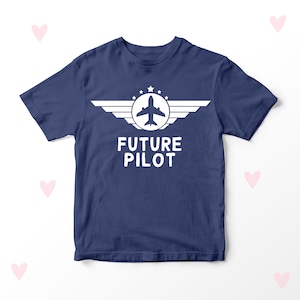 Può includere: Una maglietta blu navy con una grafica di aereo bianca e il testo "FUTURE PILOT" in bianco.