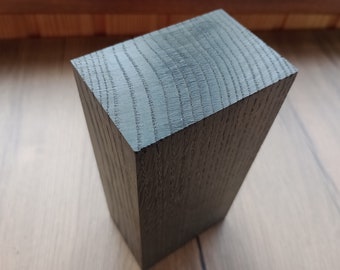 May include: A dark gray wooden block with a smooth, polished surface. The grain of the wood is visible.