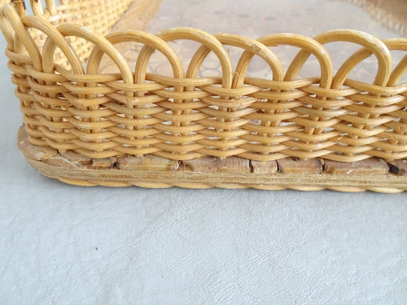 May include: A woven wicker tray with a natural wood finish. The tray has a scalloped edge and a woven base.