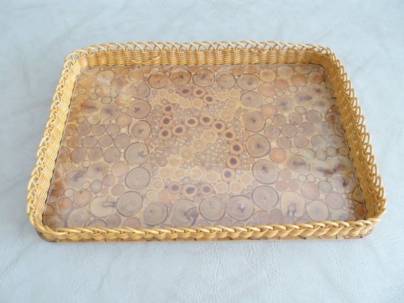 May include: A rectangular tray with a woven wicker border and a clear top. The tray's surface is made of a unique material that resembles a mosaic of wood slices.