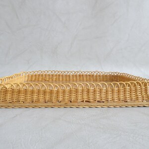May include: A rectangular woven wicker tray with a decorative scalloped edge. The tray is made of natural light brown wicker.