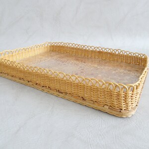 May include: A rectangular wicker tray with a woven design and a clear glass insert. The tray has a scalloped edge.