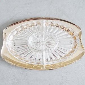 Könnte beinhalten: Eine gläserne Servierplatte mit vier Sektionen und goldfarbenem Rand. Die Platte ist klar und hat ein dekoratives, radiales Muster.