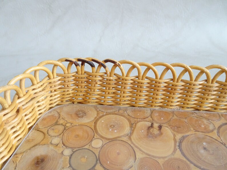 May include: A woven wicker tray with a scalloped edge and a clear glass insert with a wood veneer design. The wood veneer is made of small, round pieces of wood.