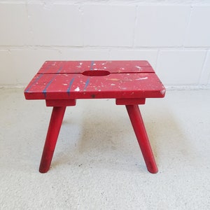 large milking stool painted red, primitive wooden stool, brutalist stool