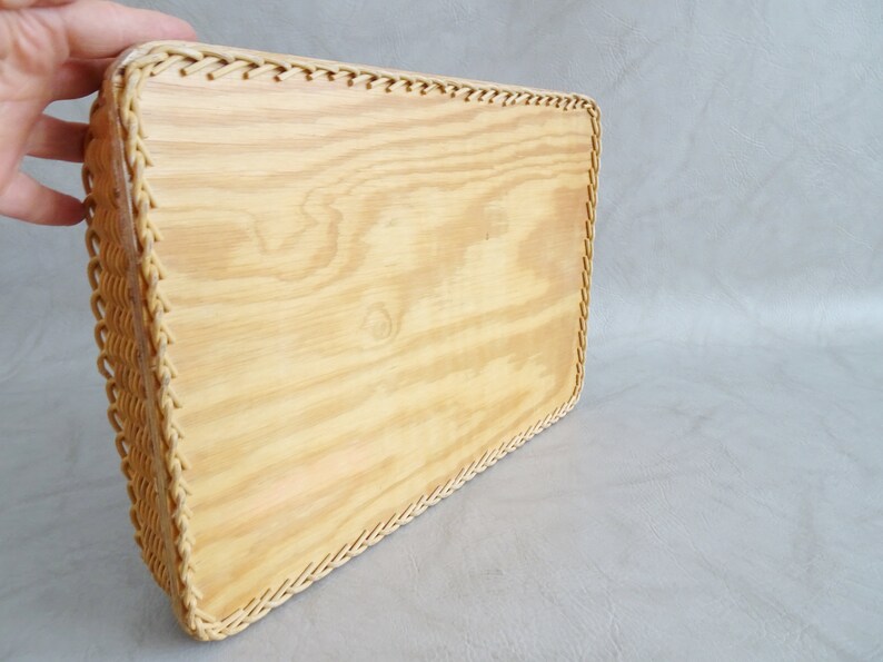 May include: A rectangular wooden tray with a woven wicker border. The tray is made of light wood and has a natural finish.
