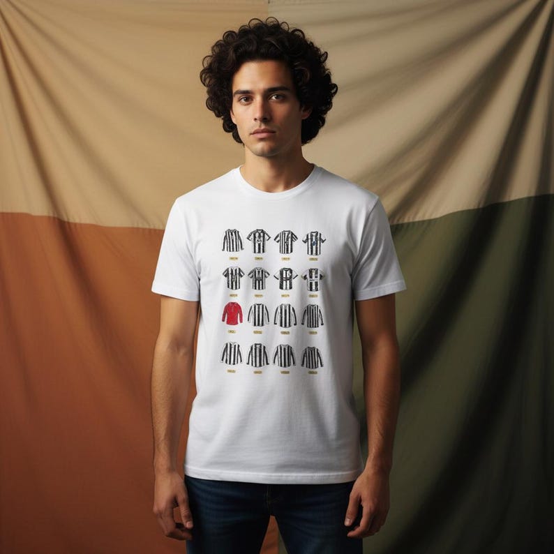 K&ouml;nnte beinhalten: Wei&szlig;es T-Shirt mit einer Grafik von Fu&szlig;balltrikots in schwarz-wei&szlig;en Streifen, mit einem roten Trikot. Die Trikots sind in einem Raster angeordnet. Die Person tr&auml;gt eine blaue Jeans.